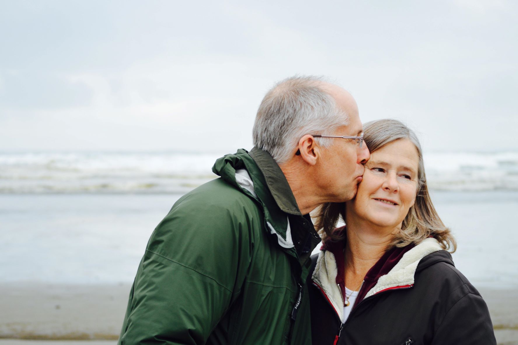 older couple embrace on a beach